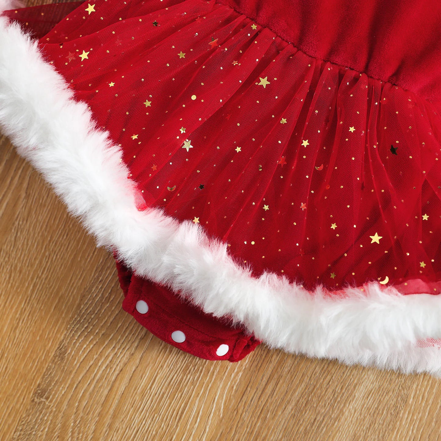 Detailed shot of sparkling red sequin skirt and soft white fur hem on baby romper.
