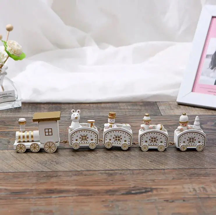 White and gold wooden Christmas train on rustic wood table with holiday background.