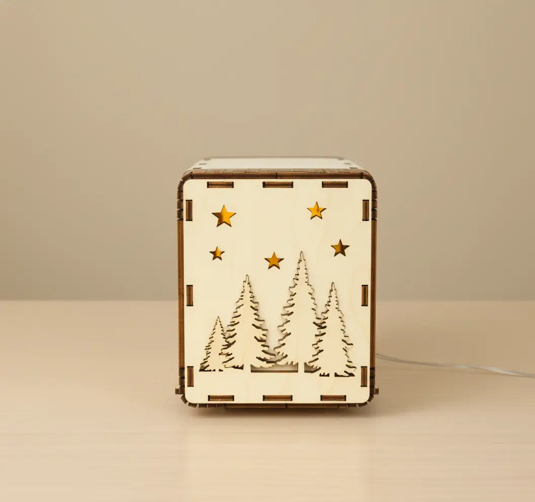 Wooden LED light box with engraved Christmas tree and star design softly lit on beige background.