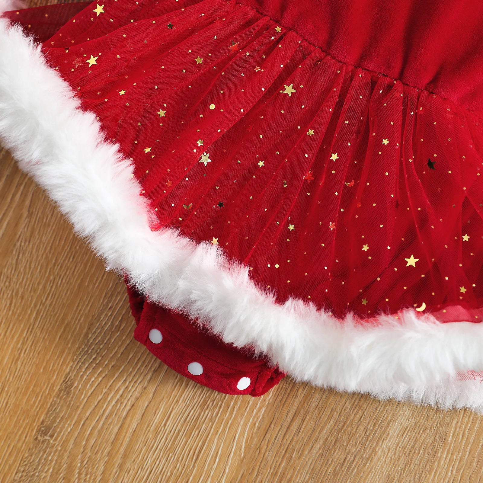 Detailed shot of sparkling red sequin skirt and soft white fur hem on baby romper.